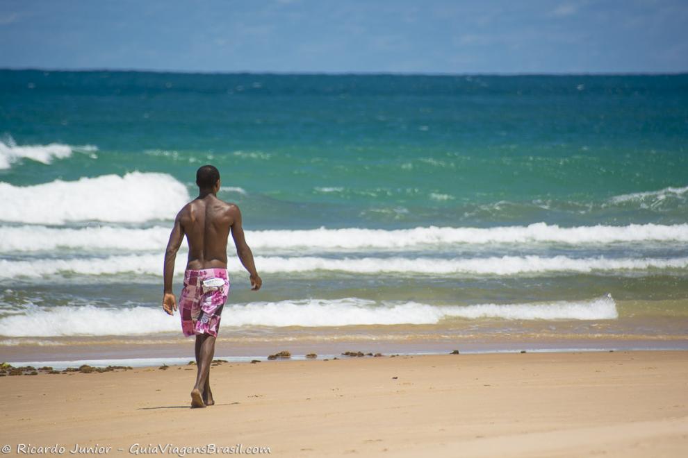 Imagem de um homem caminhando na beira do mar naPraia de Barra Grande.